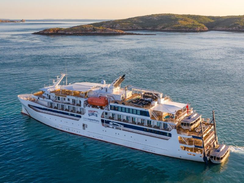 Het expeditieschip Coral Adventurer voor anker bij een tropisch eiland